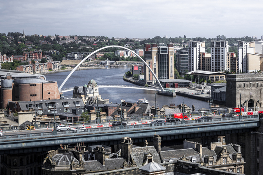 Aerial view of the Gateshead Millennium Bridge spanning the River Tyne with modern buildings and historic architecture in Newcastle upon Tyne England United Kingdom. Aerial view of the Gateshead Millennium Bridge spanning the River Tyne with modern buildings and historic architecture in Newcastle upon Tyne England United Kingdom.