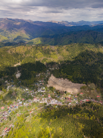Aerial view of the historic mining village of Spania Dolina nestled among lush green forests and rolling hills under a cloudy sky in Spania Dolina Banska Bystrica Region Slovakia.