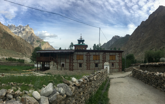 View of the traditional stone and timber building in the Hushe River Valley with stone walls and a wooden balcony set against rugged mountains and a stone fence Saling Gilgit Pakistan. View of the traditional stone and timber building in the Hushe River Valley with stone walls and a wooden balcony set against rugged mountains and a stone fence Saling Gilgit Pakistan.