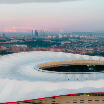 Aerial view of Riyadh Air Metropolitano Stadium with its white roof structure overlooking the urban skyline of Madrid during golden hour. Madrid Comunidad de Madrid Spain.