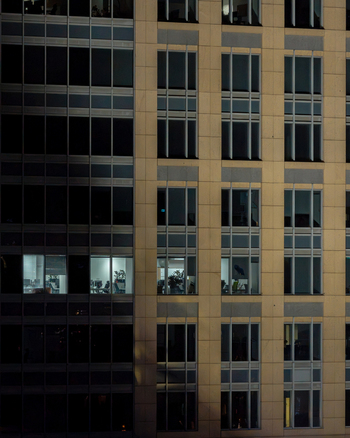 Aerial view of a modern office building facade in the financial center with illuminated windows and a grid like structure in Warsaw Masovian Voivodeship Poland.