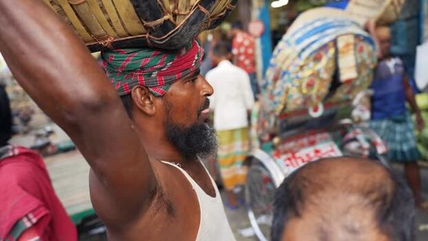 View of a porter carrying a basket at Sadarghat Bangladesh.