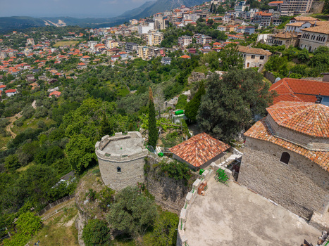 Aerial view of the historic Kruje Castle with its ancient stone fortifications red tiled rooftops and lush green hillsides in the background Kruje Durres County Albania.