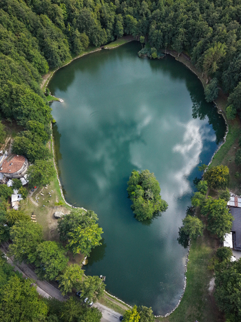Aerial view of Lago Pontini with its small central island surrounded by dense forest and reflecting clouds in Bagno di Romagna Emilia Romagna Italy. Aerial view of Lago Pontini with its small central island surrounded by dense forest and reflecting clouds in Bagno di Romagna Emilia Romagna Italy.