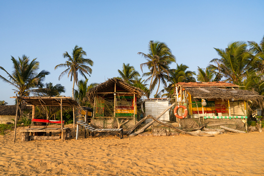 View of rustic beach shacks with thatched roofs and colorful details under palm trees on a sandy shore Galle Southern Province Sri Lanka.