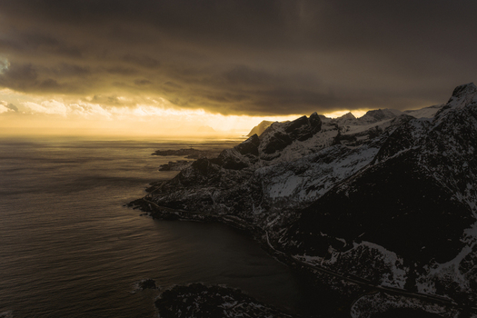 Aerial view of dramatic cliffs meeting the moody sea under a brooding sky Reinebringen Nordland Norway.