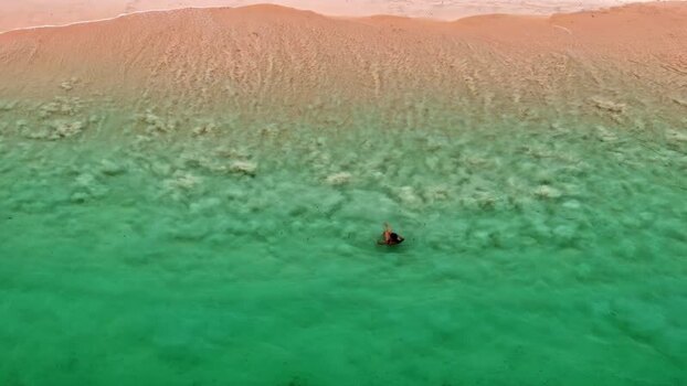 Aerial view of person swimming in turquoise water Indonesia.