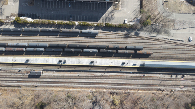 Aerial view of train cars resting on parallel tracks beside a vacant platform stark against the bare trees and empty parking lot Braintree Massachusetts United States.