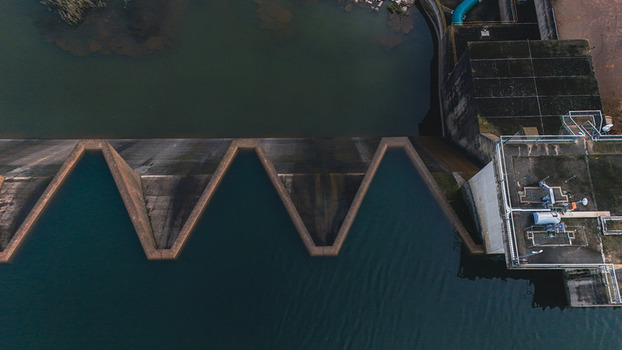 Aerial view of the Midmar Dam featuring its unique zigzag spillway and concrete infrastructure over dark water in Howick KwaZulu Natal South Africa. Aerial view of the Midmar Dam featuring its unique zigzag spillway and concrete infrastructure over dark water in Howick KwaZulu Natal South Africa.