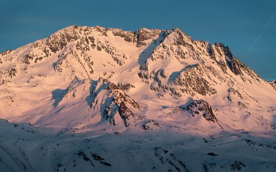 Aerial view of snow capped mountains bathed in the golden hues of sunrise or sunset Val Thorens Auvergne Rh&ocirc;ne Alpes France.