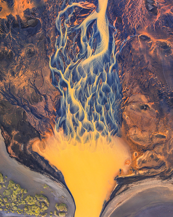 Aerial view of a glacial river delta in Iceland showing intricate braided river patterns with vibrant yellow sediment and dark volcanic sand. Aerial view of a glacial river delta in Iceland showing intricate braided river patterns with vibrant yellow sediment and dark volcanic sand.