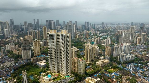 Aerial view of the dense urban skyline featuring modern high rise residential towers and sprawling city architecture under a cloudy sky in Mumbai Maharashtra India.