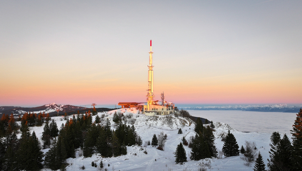 Aerial view of the Col de la Faucille telecommunications tower on a snowy mountain peak with a sea of clouds at sunset Gex Auvergne Rhone Alpes France. Aerial view of the Col de la Faucille telecommunications tower on a snowy mountain peak with a sea of clouds at sunset Gex Auvergne Rhone Alpes France.