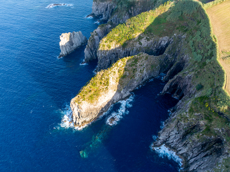 Aerial view of rugged coastal cliffs with lush green vegetation overlooking the deep blue Atlantic Ocean Ribeira Grande Azores Portugal.