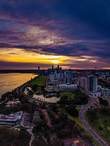 Aerial view of the Perth skyline at sunset with the Swan River lush parklands and modern skyscrapers under a vibrant colorful sky in City of Perth Western Australia Australia.