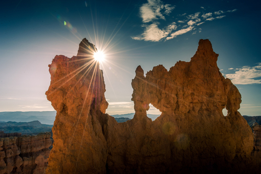 View of the sunburst behind the iconic hoodoos of Bryce Canyon National Park in Utah United States.
