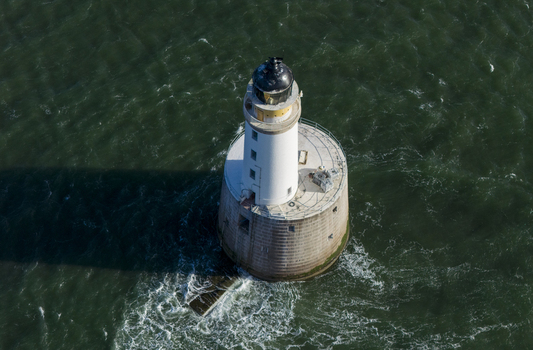 Aerial view of Rattray Head Lighthouse a white tower standing in the dark green sea with gentle waves and white foam near Peterhead Scotland United Kingdom. Aerial view of Rattray Head Lighthouse a white tower standing in the dark green sea with gentle waves and white foam near Peterhead Scotland United Kingdom.