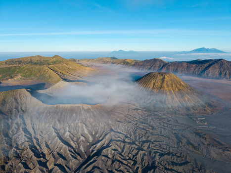 Aerial view of Mount Bromo sunrise over the volcanic caldera with mist swirling around the rugged terrain in Tosari East Java Indonesia.