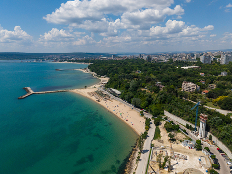 Aerial view of the coastline in Varna featuring the sandy beach the Black Sea lush greenery and the Alley First promenade under a blue sky in Varna Varna Bulgaria. Aerial view of the coastline in Varna featuring the sandy beach the Black Sea lush greenery and the Alley First promenade under a blue sky in Varna Varna Bulgaria.