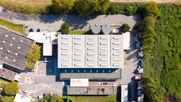 Aerial view of an industrial building with skylights surrounded by trees and paved areas in Milan Lombardy Italy.