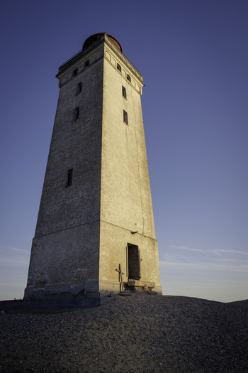 View of Rubjerg Knude lighthouse standing on a sandy dune under a clear blue sky in Lokken Denmark. View of Rubjerg Knude lighthouse standing on a sandy dune under a clear blue sky in Lokken Denmark.