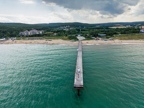 Aerial view of a long concrete pier extending into the turquoise waters of the Black Sea at the sandy beach in Shkorpilovtsi Varna Bulgaria. Aerial view of a long concrete pier extending into the turquoise waters of the Black Sea at the sandy beach in Shkorpilovtsi Varna Bulgaria.