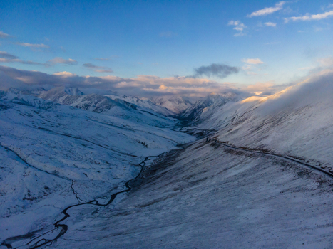 Aerial view of Babusar Pass with snow covered mountain peaks a winding road and a frozen river valley under a clear blue sky in Babusar KPK Pakistan. Aerial view of Babusar Pass with snow covered mountain peaks a winding road and a frozen river valley under a clear blue sky in Babusar KPK Pakistan.