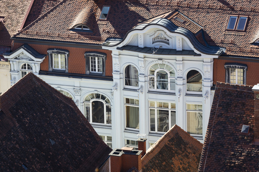 View of terracotta rooftops framing an ornate white building gleaming with sunlight a contrast of textures and colors in the urban landscape Graz Styria Austria. View of terracotta rooftops framing an ornate white building gleaming with sunlight a contrast of textures and colors in the urban landscape Graz Styria Austria.
