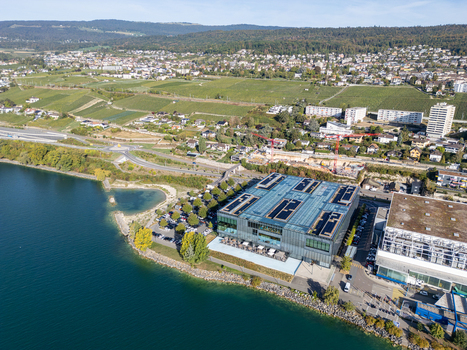 Aerial view of the Philip Morris RD Cube on the shores of Lake Neuchatel surrounded by vineyards and residential areas in Neuchatel Neuchatel Switzerland.