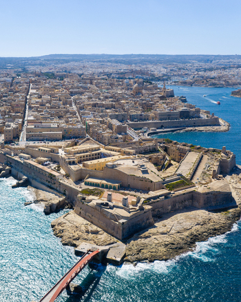 Aerial view of Fort Saint Elmo and the historic city of Valletta featuring limestone fortifications dense urban rooftops and the sea in Valletta Port Region Malta. Aerial view of Fort Saint Elmo and the historic city of Valletta featuring limestone fortifications dense urban rooftops and the sea in Valletta Port Region Malta.