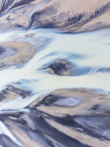 Aerial view of a glacial river with intricate patterns of sediment rich water flowing through dark volcanic sand and gravel banks Iceland. Aerial view of a glacial river with intricate patterns of sediment rich water flowing through dark volcanic sand and gravel banks Iceland.