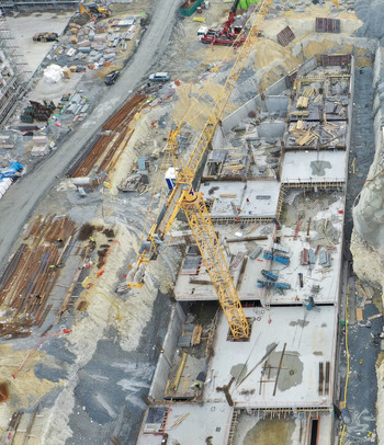 Aerial view of a busy construction site featuring a large yellow tower crane concrete foundations and organized building materials in Avcilar Istanbul Turkiye. Aerial view of a busy construction site featuring a large yellow tower crane concrete foundations and organized building materials in Avcilar Istanbul Turkiye.