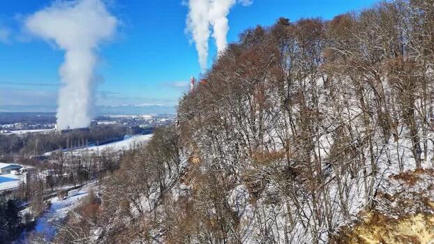 Aerial view of a snowy hillside and industrial smoke Austria.