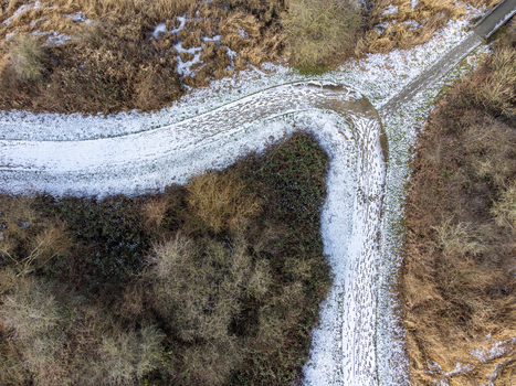 Aerial view of a snow dusted Kromslootpark where paths intersect amidst the muted browns and greens of winter s embrace Almere Flevoland Netherlands. Aerial view of a snow dusted Kromslootpark where paths intersect amidst the muted browns and greens of winter s embrace Almere Flevoland Netherlands.