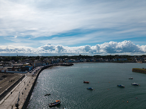 Aerial view of Donaghadee Harbour with fishing boats in the bay historic waterfront buildings and blue sky with clouds in Donaghadee Northern Ireland United Kingdom. Aerial view of Donaghadee Harbour with fishing boats in the bay historic waterfront buildings and blue sky with clouds in Donaghadee Northern Ireland United Kingdom.