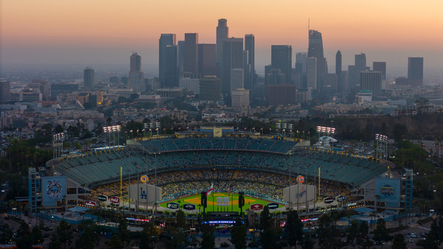 Aerial view of Dodger Stadium bathed in the warm glow of twilight against the stark silhouette of the downtown skyline Los Angeles California United States. Aerial view of Dodger Stadium bathed in the warm glow of twilight against the stark silhouette of the downtown skyline Los Angeles California United States.