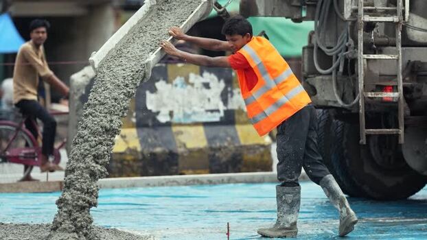 View of a worker pouring concrete from a mixer truck Bangladesh. View of a worker pouring concrete from a mixer truck Bangladesh.