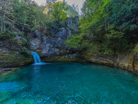 Aerial view of the Blue Eye Theth natural spring with vibrant turquoise water a small waterfall cascading down rocky cliffs and surrounding lush forest in Theth Shkoder County Albania. Aerial view of the Blue Eye Theth natural spring with vibrant turquoise water a small waterfall cascading down rocky cliffs and surrounding lush forest in Theth Shkoder County Albania.