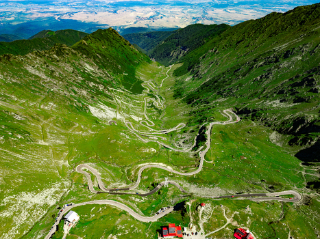 Aerial view of the winding Transfagarasan mountain road cutting through the lush green Fagaras Mountains with steep slopes and rocky terrain Curtea de Arges Judetul Arges Romania. Aerial view of the winding Transfagarasan mountain road cutting through the lush green Fagaras Mountains with steep slopes and rocky terrain Curtea de Arges Judetul Arges Romania.