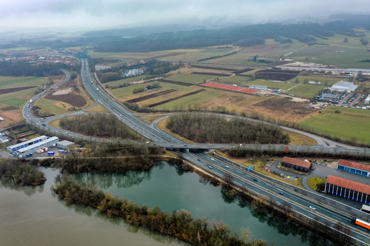 Aerial view of a highway interchange with traffic surrounding agricultural fields and a river under an overcast sky in Forchheim Bavaria Germany.