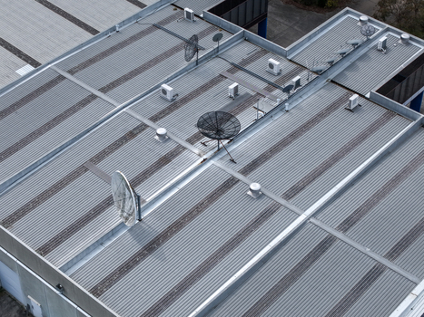 Melbourne VIC Australia 25 September 2026 Aerial view of a corrugated metal roof featuring multiple satellite dishes HVAC units and ventilation vents on an industrial building.