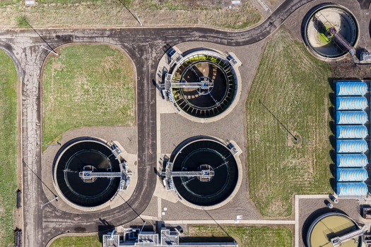 Aerial view of the wastewater treatment plant featuring circular clarifiers paved access paths and surrounding green spaces in Woodburn Oregon United States. Aerial view of the wastewater treatment plant featuring circular clarifiers paved access paths and surrounding green spaces in Woodburn Oregon United States.