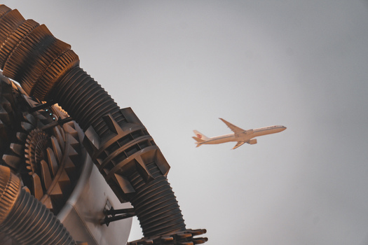 View of Universal Studios Beijing with a large mechanical structure in the foreground and an airplane flying in the sky in Beijing Beijing China.