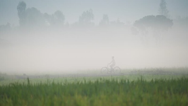 View of a person riding a bicycle through thick mist Bangladesh. View of a person riding a bicycle through thick mist Bangladesh.