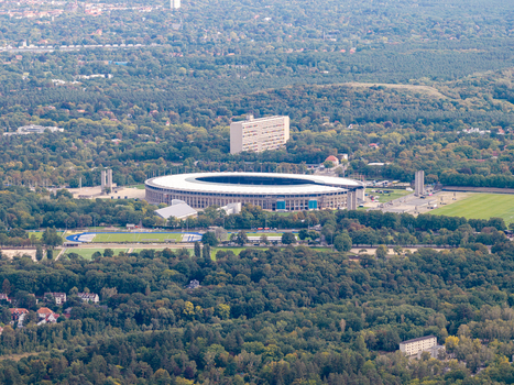Aerial view of Olympiastadion Berlin surrounded by lush green forest and parkland in the city Berlin Berlin Germany.