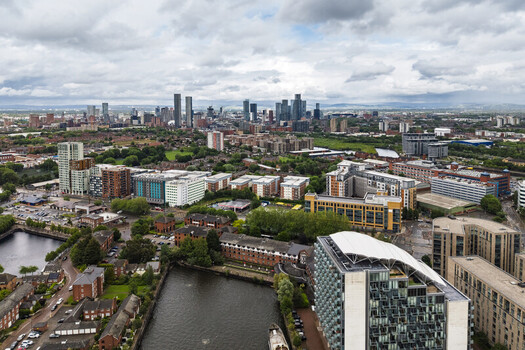 Aerial view of MediaCityUK and the surrounding urban landscape with modern residential buildings waterfront areas and the distant Manchester skyline in Salford England United Kingdom. Aerial view of MediaCityUK and the surrounding urban landscape with modern residential buildings waterfront areas and the distant Manchester skyline in Salford England United Kingdom.