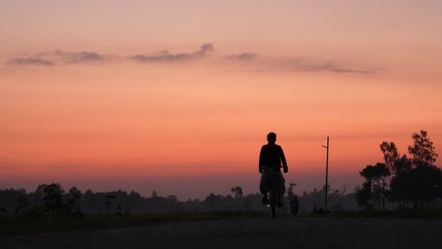 View of a person riding a bicycle at sunrise in Bogura Bangladesh. View of a person riding a bicycle at sunrise in Bogura Bangladesh.