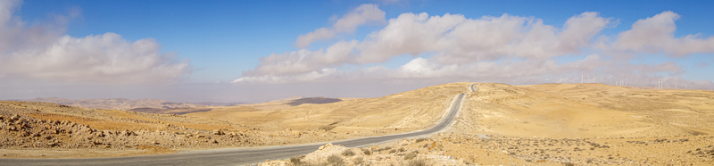View of the vast Wadi Rum Desert landscape with a winding asphalt road stretching through the arid terrain in Wadi Rum Village Aqaba Governorate Jordan. View of the vast Wadi Rum Desert landscape with a winding asphalt road stretching through the arid terrain in Wadi Rum Village Aqaba Governorate Jordan.