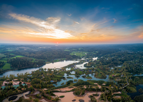 Aerial view of a serene landscape featuring winding lakes dense forests and marshy terrain under a vibrant sunset sky in Latvia. Aerial view of a serene landscape featuring winding lakes dense forests and marshy terrain under a vibrant sunset sky in Latvia.