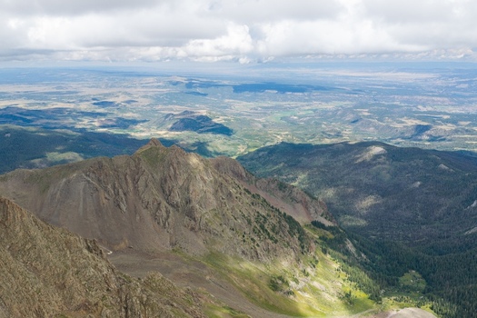 Aerial view of Mount Sneffels in the San Juan Mountains featuring rugged rocky peaks deep valleys and expansive alpine terrain under a cloudy sky in Ouray County Colorado United States. Aerial view of Mount Sneffels in the San Juan Mountains featuring rugged rocky peaks deep valleys and expansive alpine terrain under a cloudy sky in Ouray County Colorado United States.